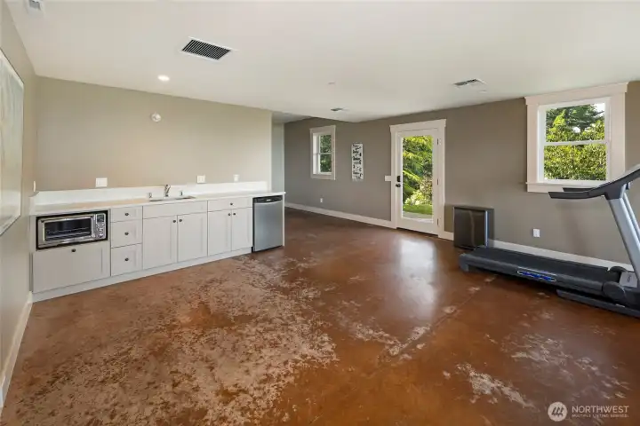 Lower-level kitchenette with sink, cabinetry, and beverage fridge—ideal for guests or extended stays.