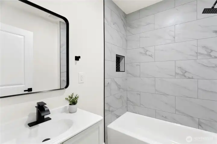Stylish full bath with tiled shower and niche detail.