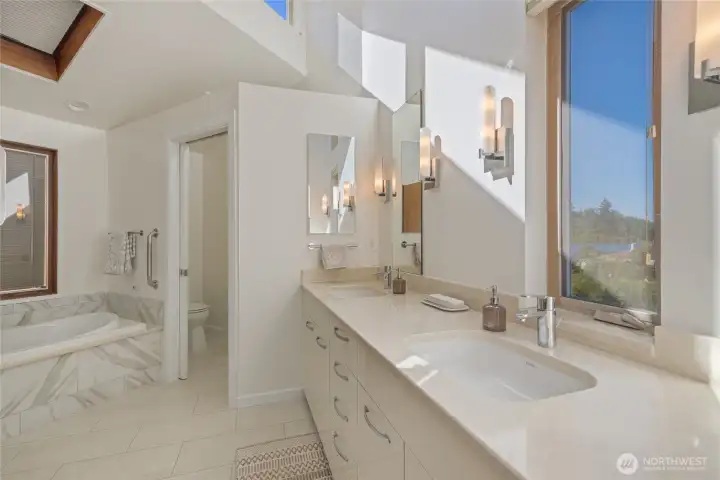 Warm natural light fills the primary bathroom. His and hers sinks!