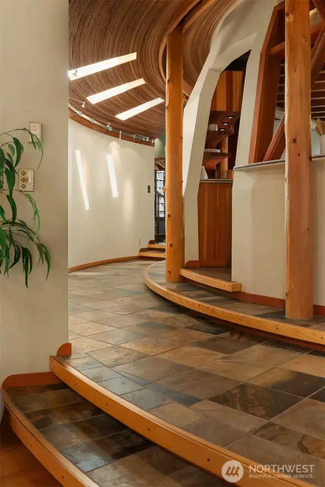 Slate floors and a wood inlaid staircase lead to a curved hallway that frames the striking central dome.