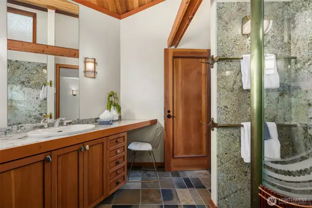 Main floor bath with walk-in slate shower, wood details, vaulted ceilings, and natural light from a well-placed window.