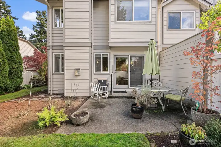 Peaceful private patio enveloped by mature plants and trees.