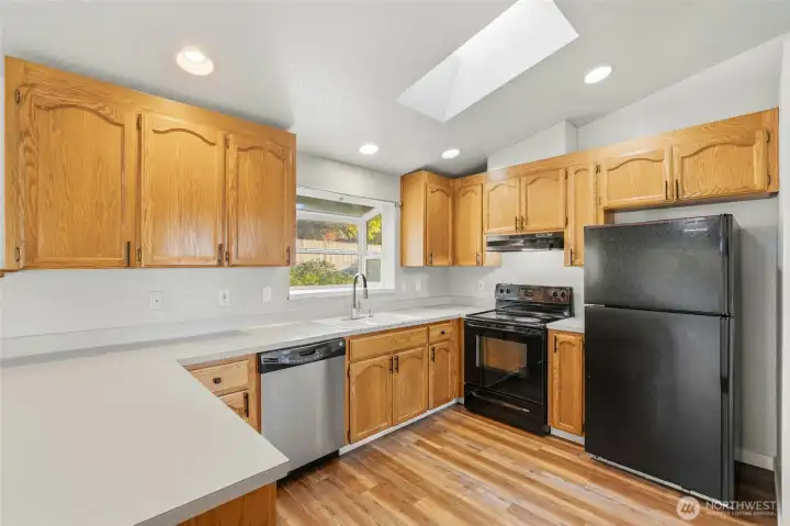 Large kitchen with garden window and ample oak cabinetry.
