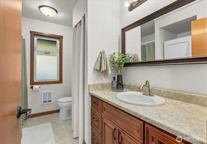 Upstairs hall bathroom with stacking washer and dryer and shower