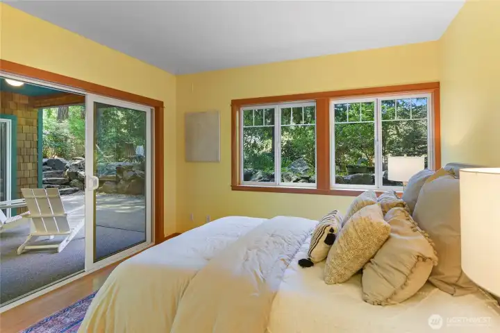Daylight basement bedroom #2 with covered patio access and pleasant natural views.