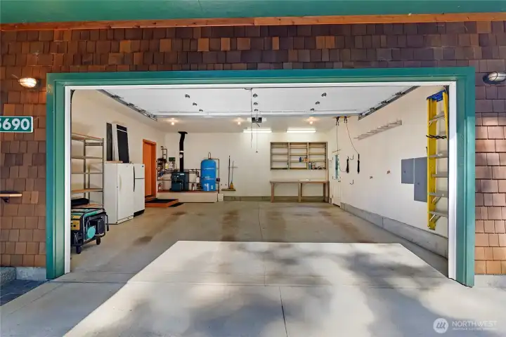 Heated garage with stubs for hot and cold water, descending floor for run-off from indoor car washing, bicycle and folding chair hanging storage, and generator, freezer, and refrigerator included in the sale.