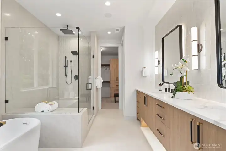 Spa-inspired bath with frameless glass-enclosed shower and full-height tile surround. Ceiling rain shower, wall rain shower head, and handheld shower wand.