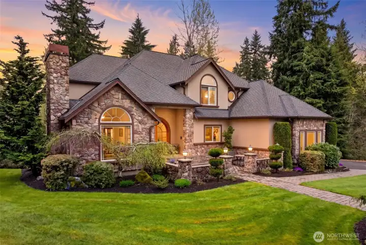 Hand-laid stonework, arched windows, and a soaring chimney glow against a painted Pacific Northwest sky, showcasing the craftsmanship and timeless architectural character that set this estate apart. Evenings here feel like a permanent vacation.