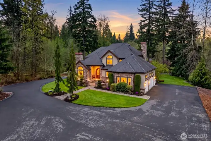 The expansive circular driveway, three-car garage, and glowing twilight ambiance set the stage for effortless entertaining and gracious arrivals.