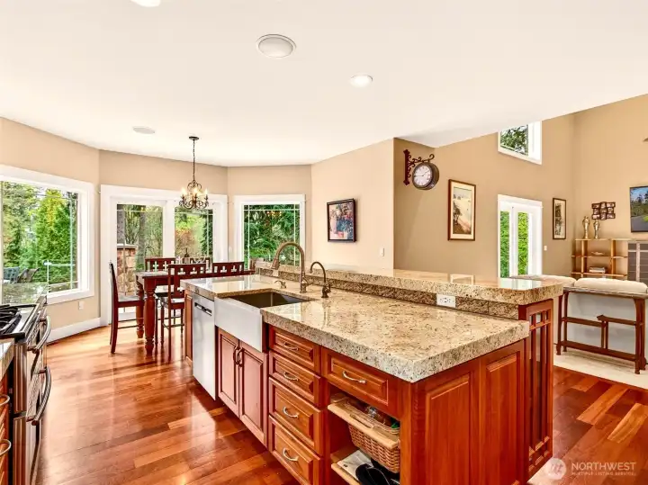 The chef's kitchen features an oversized granite island with deep sink, gas range, and walls of windows overlooking the lush, private grounds. Updated countertops and abundant prep space make daily cooking and entertaining equally effortless.