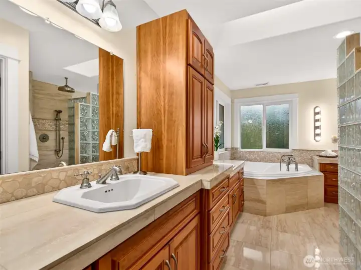 The spa-style primary bath offers dual vanities, custom cherry cabinetry, abundant storage, and direct access to a generous walk-in closet.