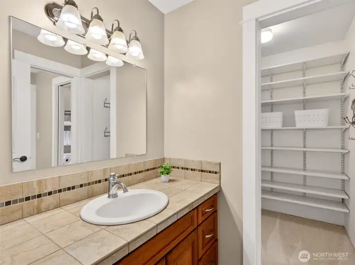 The adjoining Jack-and-Jill style bath features a tile-topped vanity, generous storage, and a walk-in linen closet for ultimate organization. Warm circulation-pump flooring keeps things cozy underfoot.