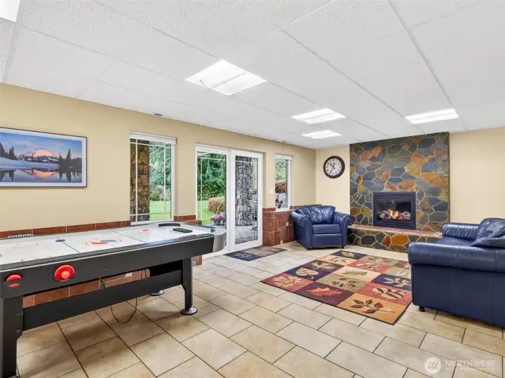 The expansive lower-level recreation room features heated tile floors, a stone-faced gas fireplace, and sliding doors to the back patio for true indoor-outdoor enjoyment. Built for game nights, movie marathons, and effortless entertaining.