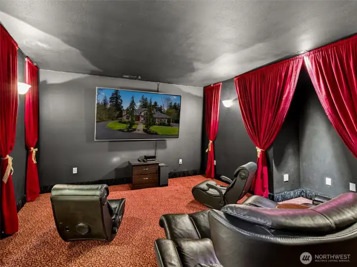 The dedicated home theater room features dramatic curtained walls, pre-wired panels for a projector setup, and rich acoustic ambiance. Movie nights at home rival the cinema experience.