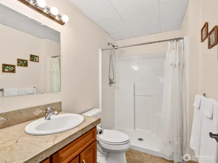 The lower-level three-quarter bath features heated marble floors, a tile-topped vanity, and a full-size shower for guest-ready convenience. A perfect complement to the basement bedroom and recreation areas.