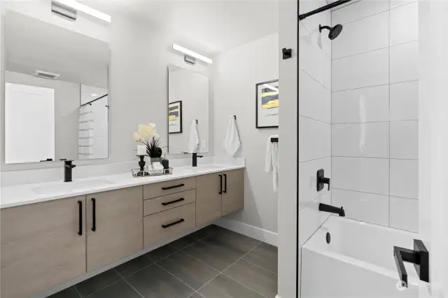 Elegant bathroom with dual vanities, sleek black fixtures, and a modern bathtub.