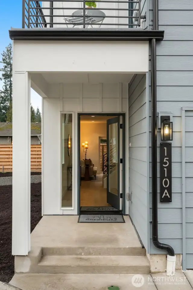 Welcome home. A sleek covered entry welcomes you in with modern lines and warm lighting—yes, that’s the first glimpse of your stunning new space just beyond the open door!