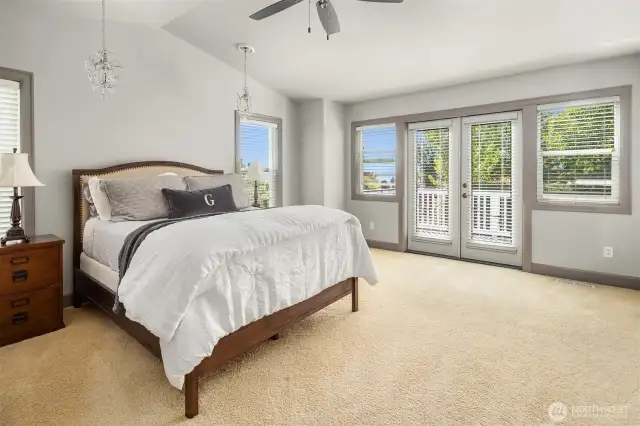 Move upstairs to the wonderful primary suite! The pitched ceiling creates great character while ample windows and french doors provide lovely peak-a-boo views of beautiful Lake Washington and the Seattle skyline.