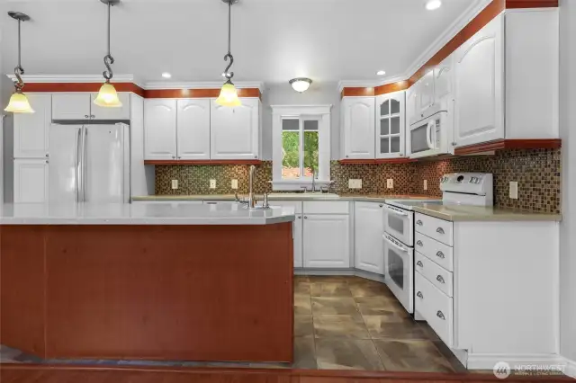 Lovely kitchen with wonderful details! Crown molding, double oven, solid surface counter top, glass-door corner cabinet--and heated tile floors!