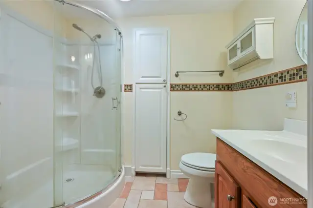 3/4 bath in Primary offers heated tile floors, built-in cabinet with pull-outs, solar tube for natural light, and corner shower.