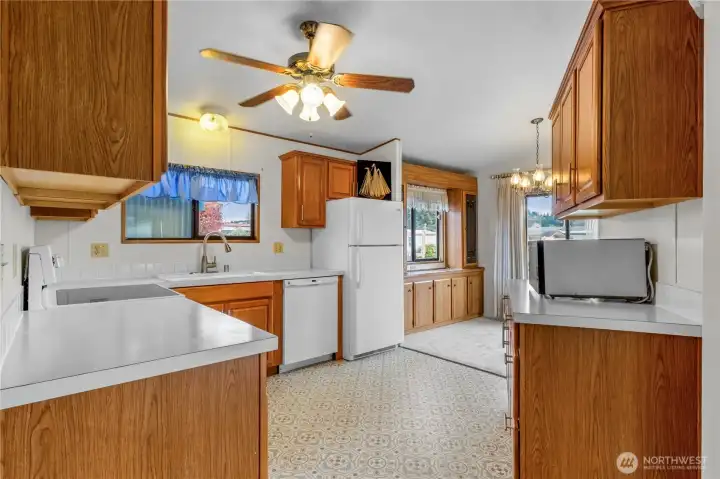 Bright and welcoming kitchen featuring classic wood cabinetry, crisp white countertops, and easy flow into the dining area and living room.
