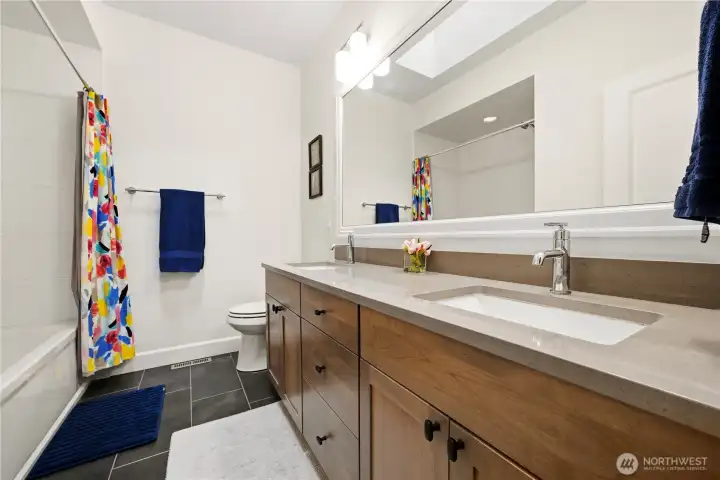 Full upper level hall bathroom with dual sinks, large mirror, and quartz counter.