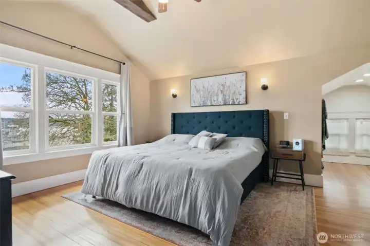 Primary suite, vaulted ceilings, ceiling fan, wall sconces, fir flooring and walk in closet on the right.