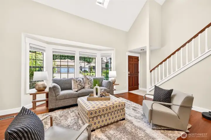 Two-story ceilings and a wall of windows flood the front living space with natural light, delivering immediate volume and warmth from the moment you step through the door.