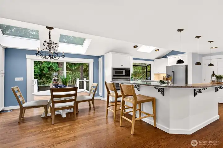 Vaulted ceilings, dual skylights, and a glass sliding door to the back deck bathe the dining nook and updated white kitchen in natural light, creating a bright, airy hub for daily life.