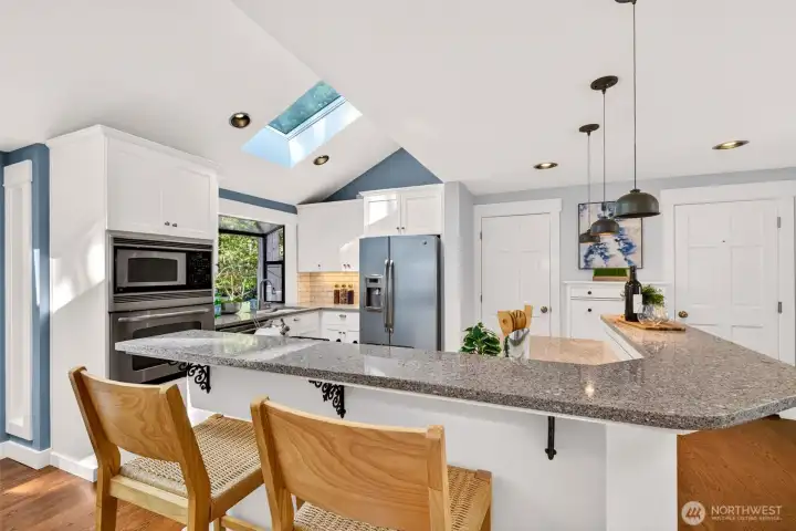 Stainless appliances, granite counters, and a gas cooktop on the island deliver a true cook's kitchen that opens directly to the living spaces beyond.
