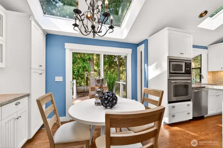 A vaulted ceiling, oversized skylight, and slider to the back deck flood the breakfast nook with natural light and a direct connection to the wooded backyard.
