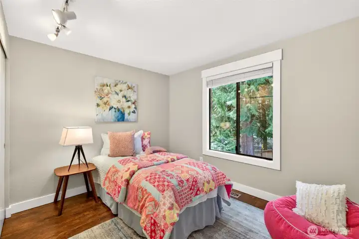 A second main-floor bedroom enjoys a tranquil window view of the surrounding evergreens, delivering a quiet, restorative retreat just steps from the main living areas.