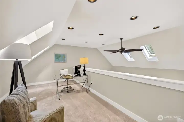 The versatile upper-level loft enjoys vaulted ceilings, multiple skylights, and recessed lighting, offering a flexible bonus space for a home office, studio, or quiet retreat.