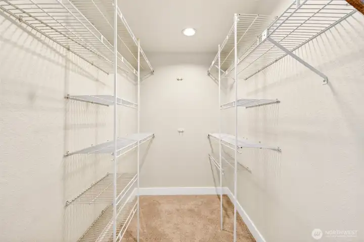 A spacious walk-in closet with custom shelving on both sides delivers the kind of dedicated storage that makes daily routines effortless.