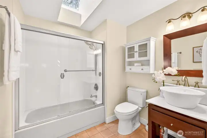 The primary full bath features a tub-shower combination, vanity with vessel sink, and a skylight overhead that bathes the space in natural light all day long.