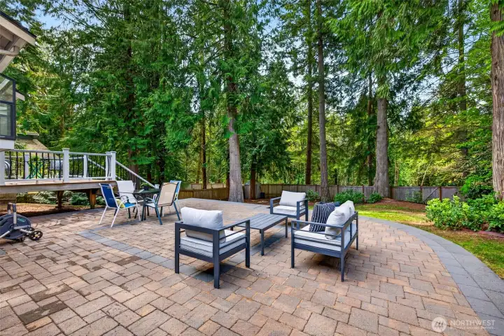 A sweeping curved expanse of new pavers extends entertaining space well into the backyard, blending hardscape and natural surroundings for a true outdoor living room feel.