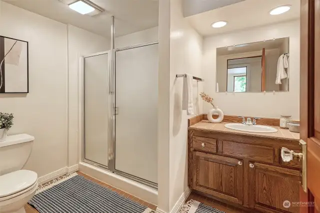 Lower level 3/4 bathroom with Terracotta “look” tile flooring, oak vanity and large shower with glass door.