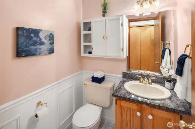 Guest bathroom is located in hall across from double-wide coat closet.