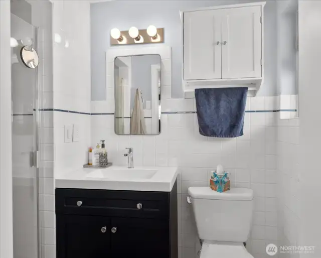 Crisp white tile with subtle navy accent * Modern vanity with sleek fixtures
