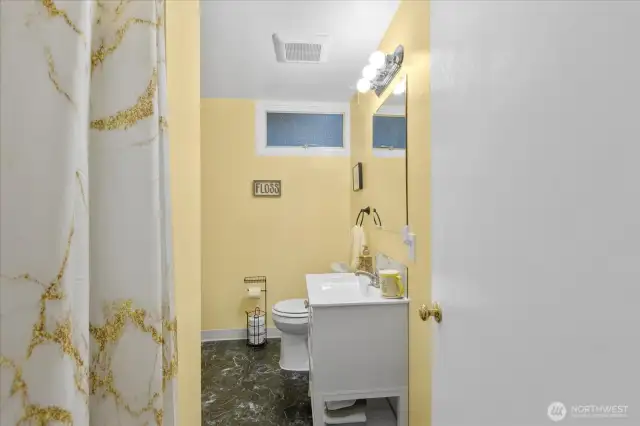 Bright and welcoming ¾ bath * Modern white vanity * Soft yellow walls add warmth and charm