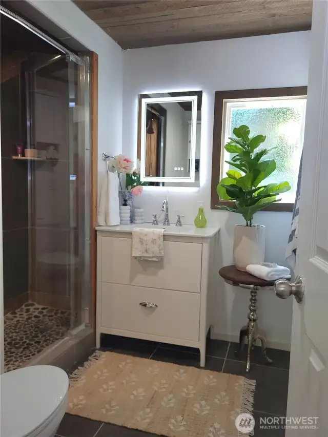 Large tiled shower, with tile details and wood ceiling for a custom touch.