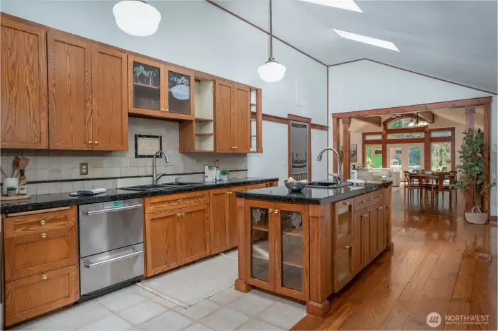 Spacious, light-filled kitchen featuring warm wood cabinetry, sleek countertops, and a large center island with additional storage and prep space.