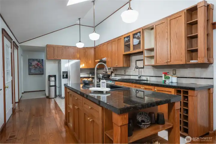 Beautifully designed kitchen with rich wood cabinetry, granite countertops, and a large center island featuring a secondary sink