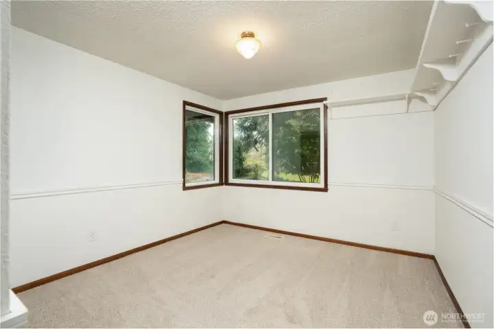 Bright and comfortable bedroom featuring soft carpeting, large windows with peaceful outdoor views, and a functional layout. Includes convenient closet space and plenty of room to personalize.