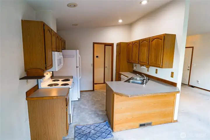 The kitchen is ready for your personal touch. Oak cabinetry and a peninsula counter offer plenty of workspace, with a slider just steps away leading to the wraparound deck.