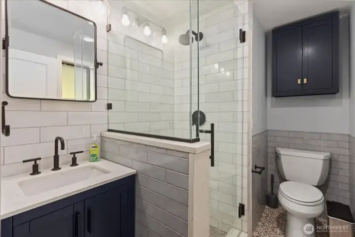 Beautifully remodeled primary bathroom en-suite with heated floor, marble tile shower, ceramic tile floor, new vanity, new mirror and lighting.