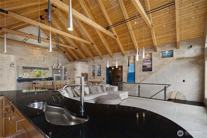 Vaulted wood ceilings, timber-frame accents, stone finishes, a glass staircase, and custom lighting showcase the home’s distinctive craftsmanship.