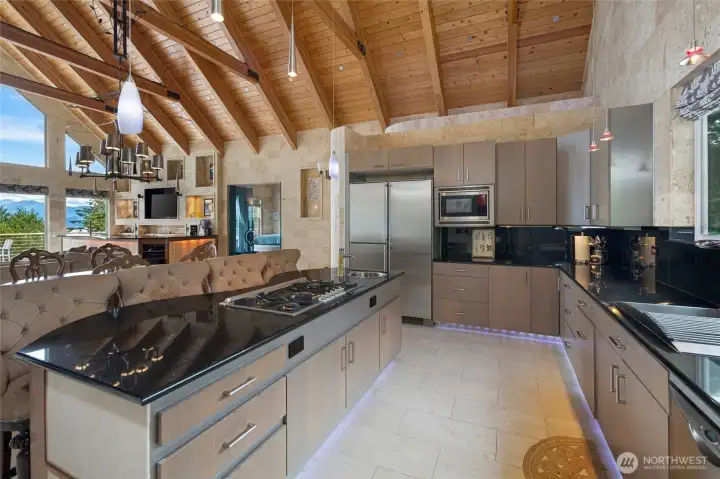Well-appointed kitchen with granite counters, extensive cabinetry, stainless appliances, double ovens, and a central cooktop island.