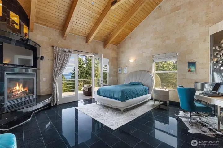 Spacious primary suite features vaulted fir ceilings, polished stone flooring, a propane fireplace, and access to a private view deck.