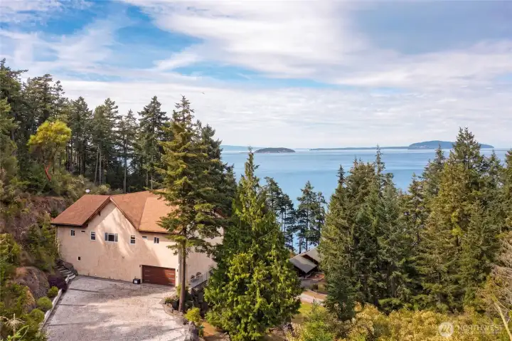 Aerial view of the custom San Juan Island residence privately positioned among mature evergreens with expansive marine views.